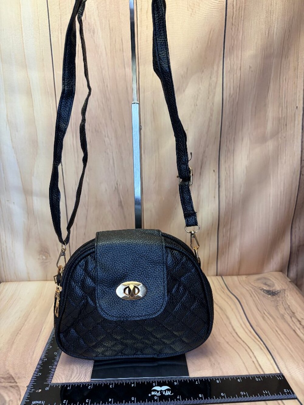 Black faux-leather quilted crossbody bag featuring a gold-tone closure